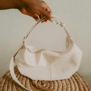 Elegant white handbag held by hand, showcasing minimalist design and fashion.