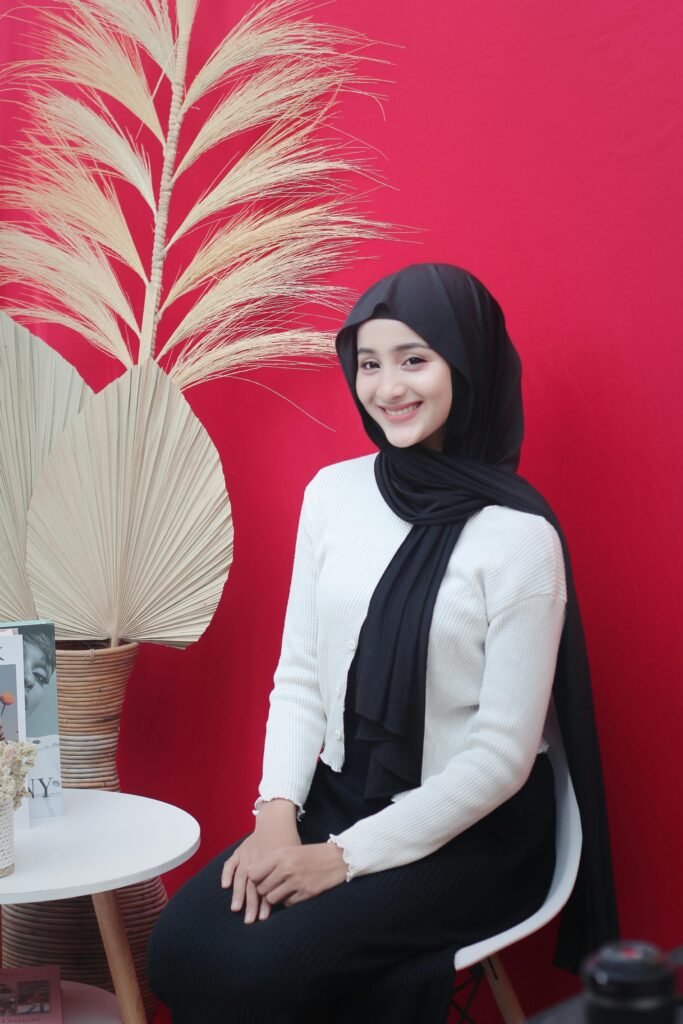 pexels-photo-29671432-29671432 Elegant portrait of a young woman wearing a hijab against a vibrant red background.